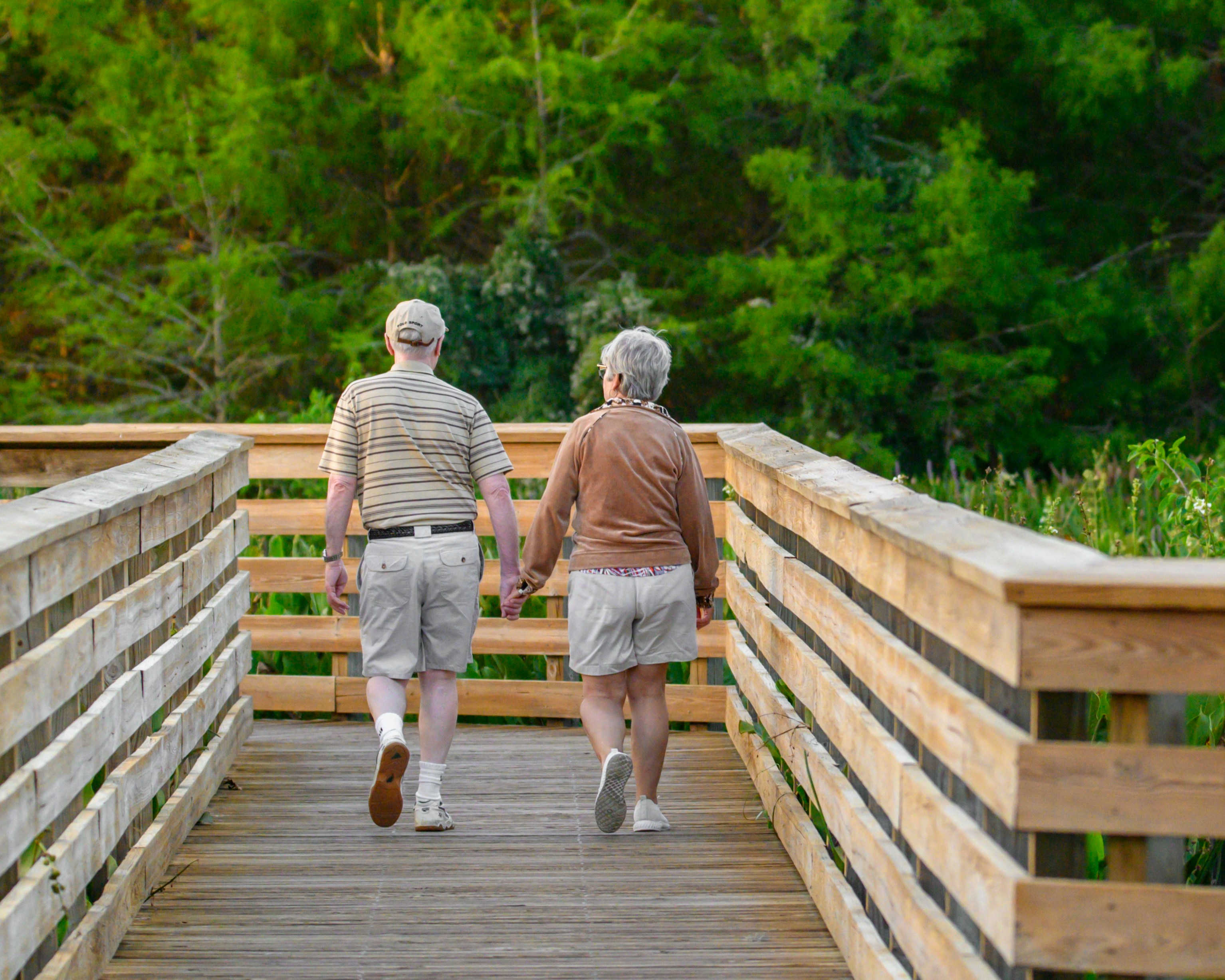 A senior couple walking together on a wooden boardwalk