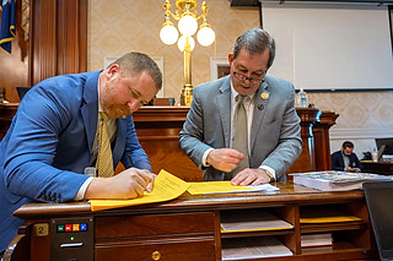 Rep. Robbins signing legislation with a colleague